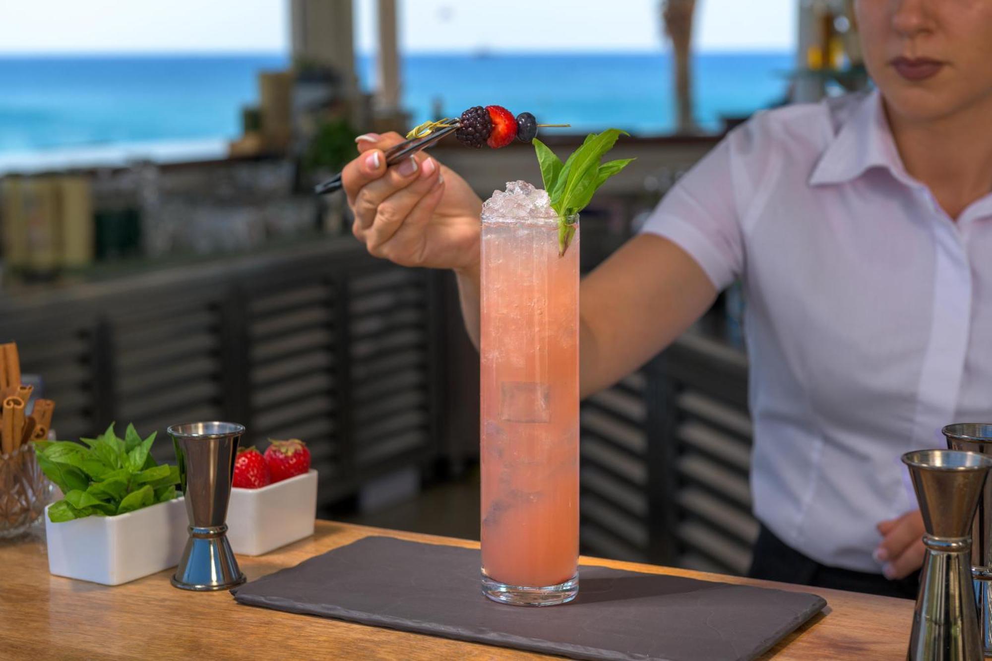 Rodos Palladium Leisure & Wellness Kallithea  Екстер'єр фото A bartender garnishes a cocktail with a fruit skewer.